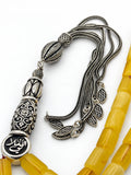 Close-up of the engraved sterling silver medallion and silver tassel of a Baltic amber tasbih by Maison Assam